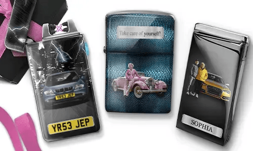 Three metal lighters featuring personalized designs. The left lighter shows a city skyline and a couple beside a car with 'BESTE OMA DER WELT'. The middle lighter depicts a pink vintage car with 'HAB DICH LIEB OMA' above. The right lighter displays a blue car and a license plate. Pink ribbons add a gift-like context.