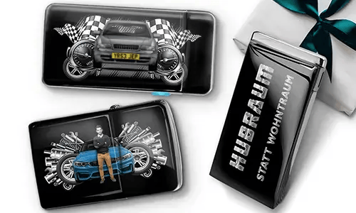 Geschenkset mit Auto-Themen-Metallbehältern, die Bilder eines grünen Sportwagens, karierten Flaggen und Motor-Motiven zeigen. Enthält ein Zigarettenetui mit der Aufschrift „Hubraum Statt Wohntraum“.