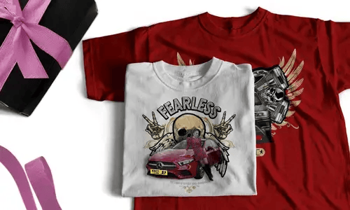 Zwei T-Shirts: weiß mit FEARLESS, Schädel, Heiligenschein, Handzeichen, rotem Auto; rot mit Flügelschädel