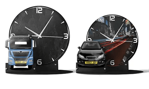 Two decorative clocks with model vehicles: left with black marble face and blue truck, right with cityscape and red sports car