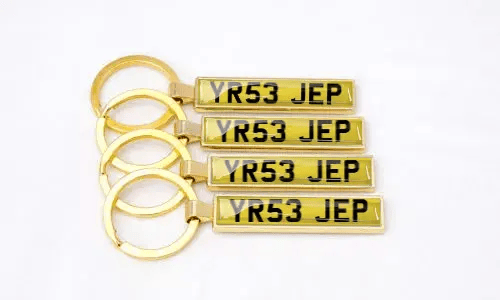 Llaveros dorados de placa de matrícula muestran números personalizados organizados juntos