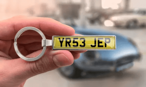 Silver license plate keychain shows personalized numbers while held in hand