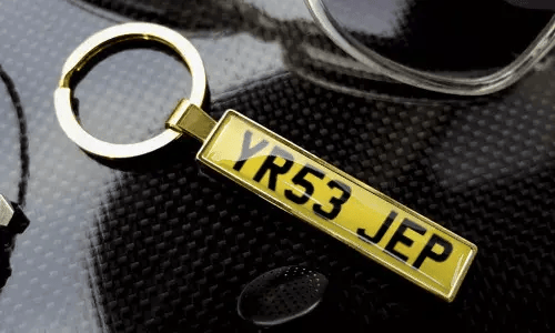 Gold license plate keychain displays engraved text in a polished metal frame