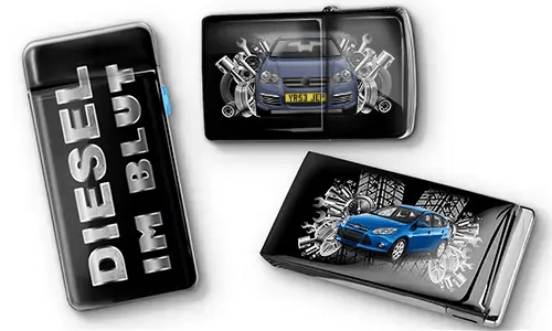 Drei schwarze Feuerzeuge mit Auto-Motiven und metallischen Akzenten. Eines trägt den Text „DIESEL IM BLUT“, die anderen zeigen rote und blaue Autos mit mechanischen Motiven. Ein sportlicher Ton wird vermittelt.