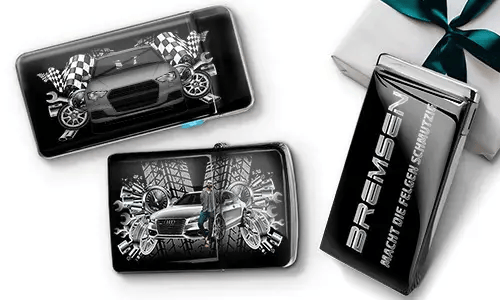 Car-themed wallets featuring sleek cars, checkered flags, and tire patterns on a black background. Beside them, a black gift box with silver text.
