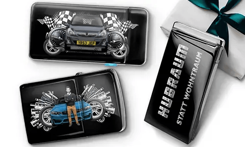 Geschenkset mit Auto-Themen-Metallbehältern, die Bilder eines grünen Sportwagens, karierten Flaggen und Motor-Motiven zeigen. Enthält ein Zigarettenetui mit der Aufschrift „Hubraum Statt Wohntraum“.