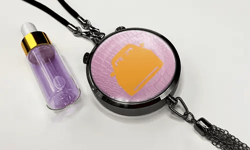 Pendant with pink background and white sports car, next to purple dropper bottle with gold cap