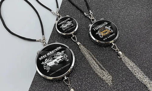 Three black pendants with chains: each with car graphic and German tuning slogan on glittery surface