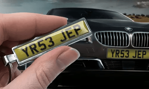 Portachiavi a forma di targa in stile fumetto con numero personalizzato, tenuto in mano vicino alla targa dell’auto corrispondente