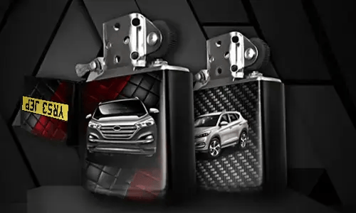 Two metallic lighters with silver SUV designs: one front view on tread background, one side view with carbon texture, small rectangular object in corner