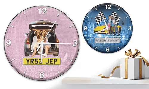 Two wall clocks with female figures and cars: left with trunk scene on pink texture, right with yellow sports car and racing flags over cityscape