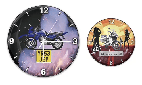 Two wall clocks with motorcycle themes: left with blue bike and flame background, right with white bike and sunset