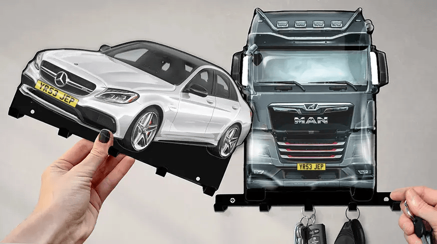 Wandmontierter Schlüsselhalter mit abnehmbaren Formen eines weißen Mercedes-Benz und eines schwarzen MAN-LKWs, jeweils mit Haken für Schlüssel