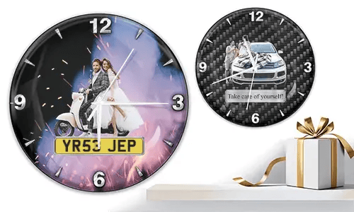 Zwei Wanduhren mit romantischen Fahrzeugmotiven: links mit Hochzeitspaar auf weißem Roller und Feuerwerk, rechts mit Paar und Auto auf Carbon-Hintergrund